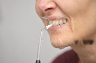Frau reinigt ihre Zähne mit einem Munddusche